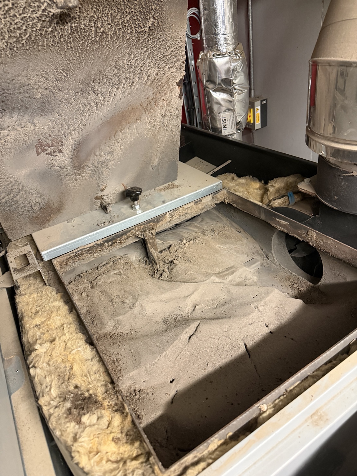 Heavy ash and combustion deposits inside the opened Fröling P4 400 biomass boiler before cleaning