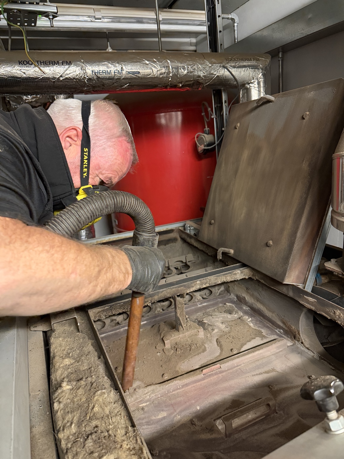 Envirowarm engineer vacuuming ash from the open Fröling P4 400 biomass boiler in Braithwaite near Doncaster